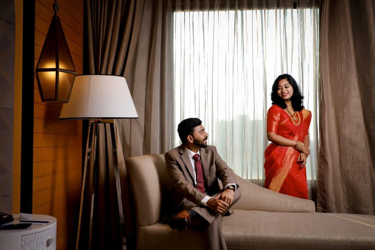 Couple beside a window with long curtains and a shaded lamp