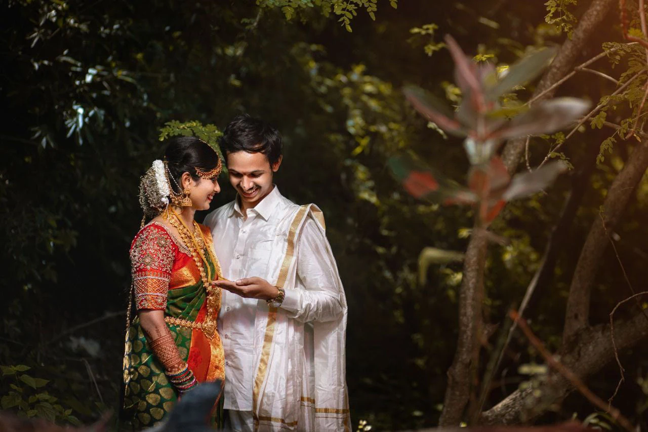 Couple looking down together beneath green trees