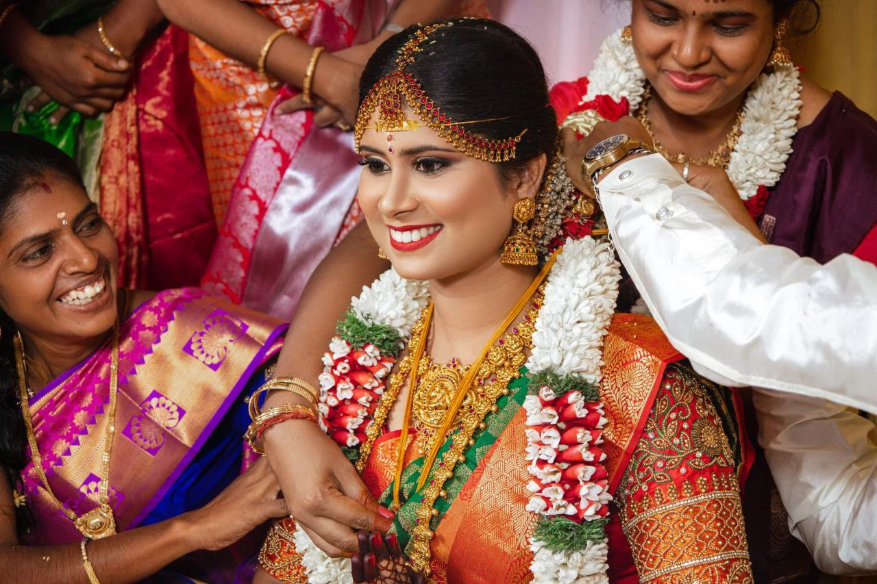 A woman smiling as people adjust flowers around her