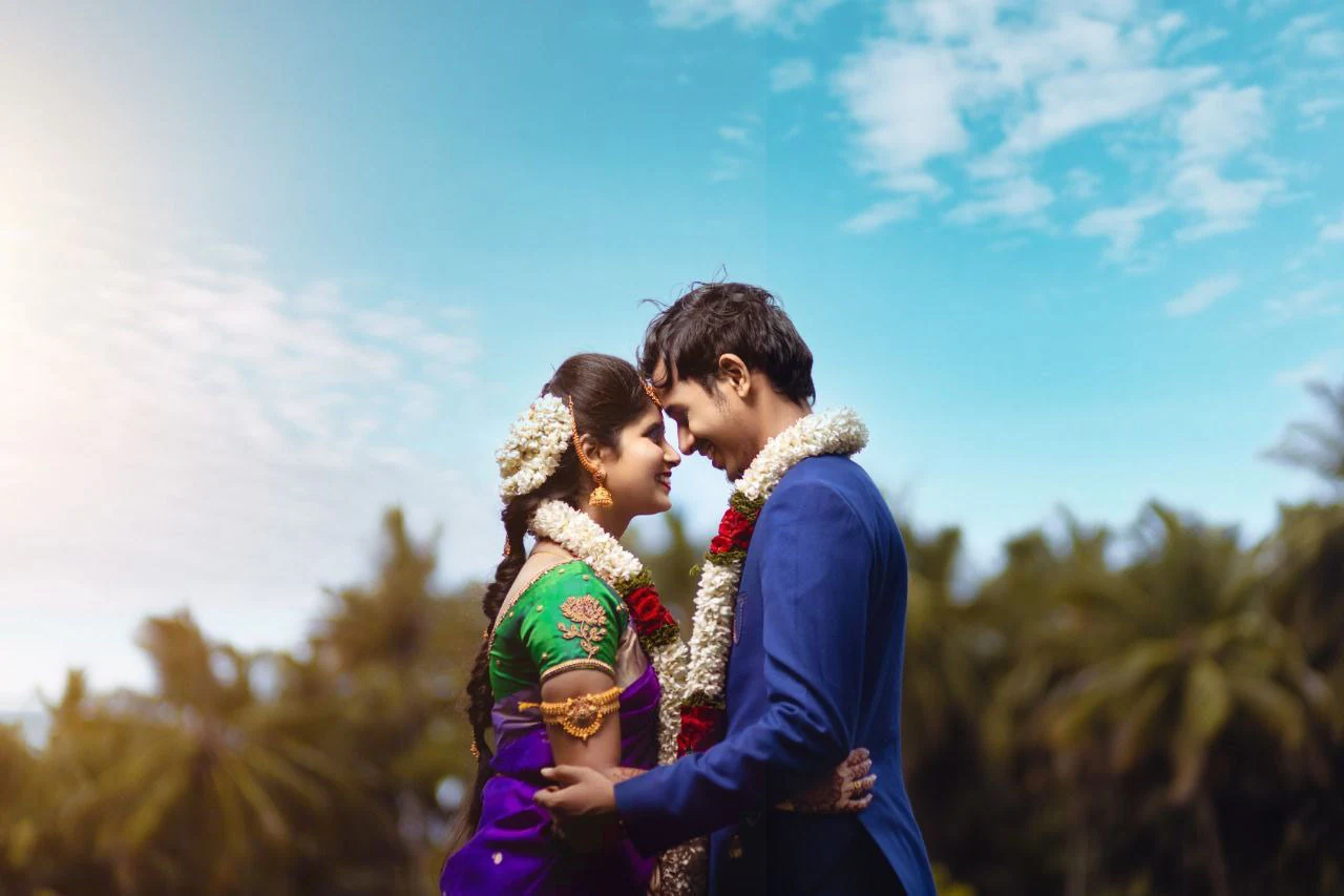 Couple standing close together under an open blue sky