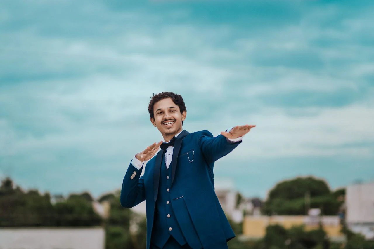 A man in a blue suit smiling with his hand outstretched