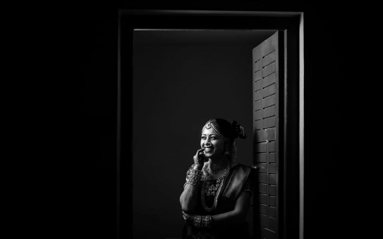Black-and-white portrait of a woman sitting beside a window