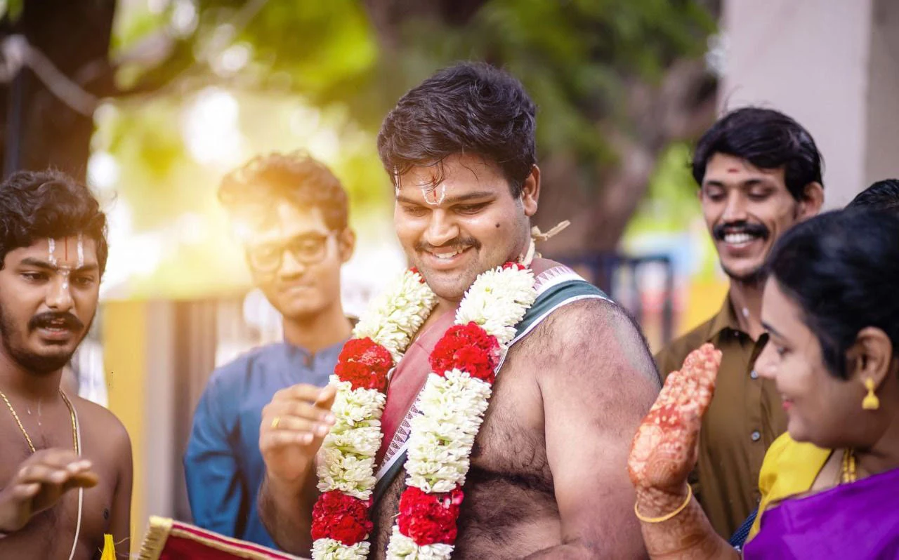 A smiling man surrounded by people during a wedding ceremony