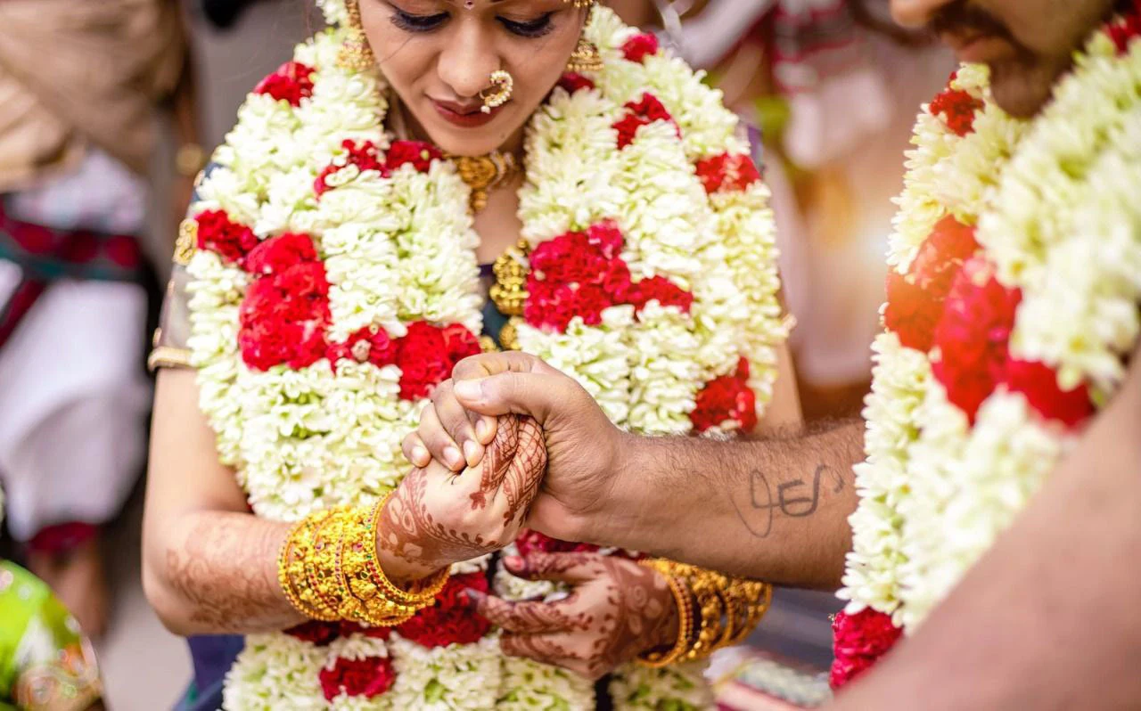 Close view of hands meeting between strands of flowers