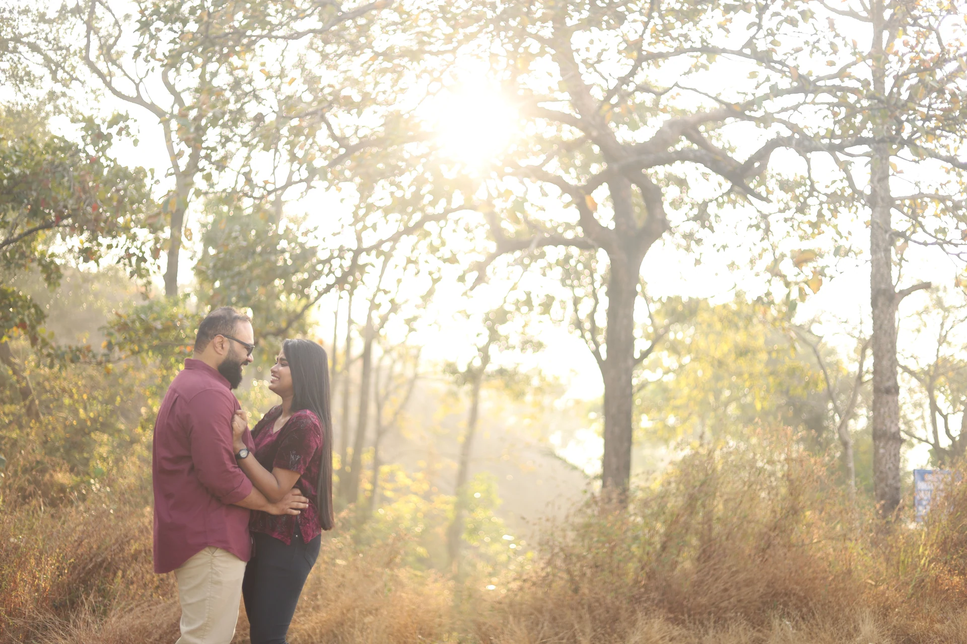 Couple looking at each other with sunlight filtering through the trees