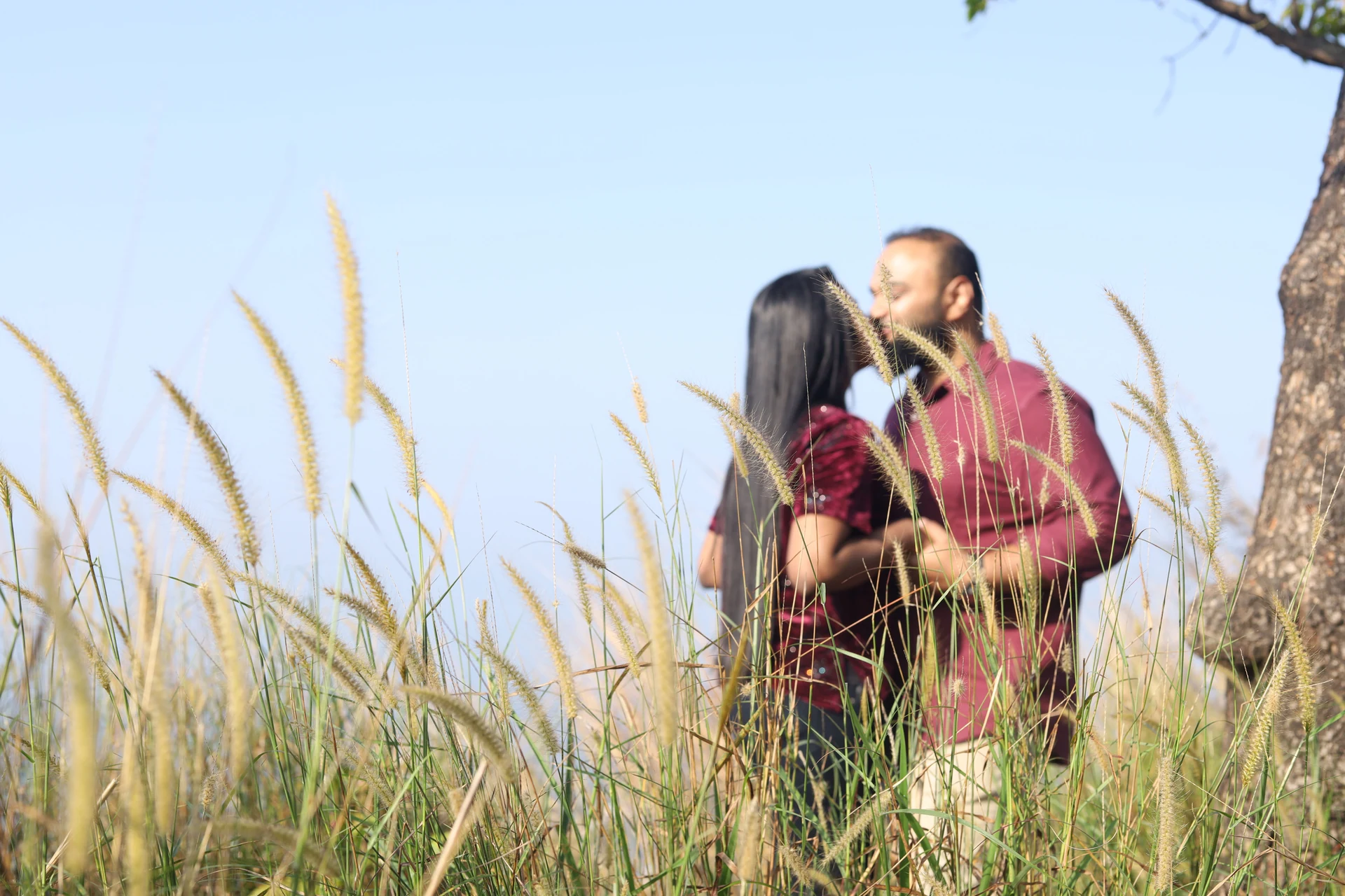 Couple leaning towards each other among tall grasses