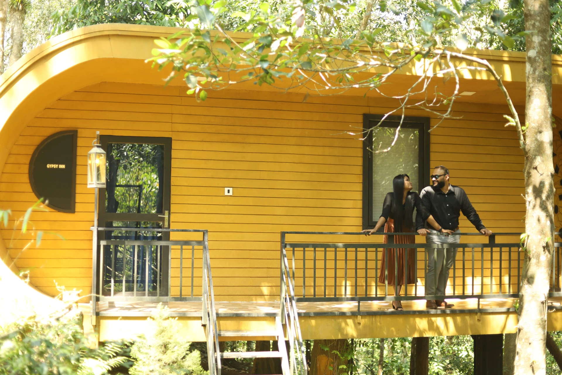 Couple leaning towards each other outside a yellow wooden cabin