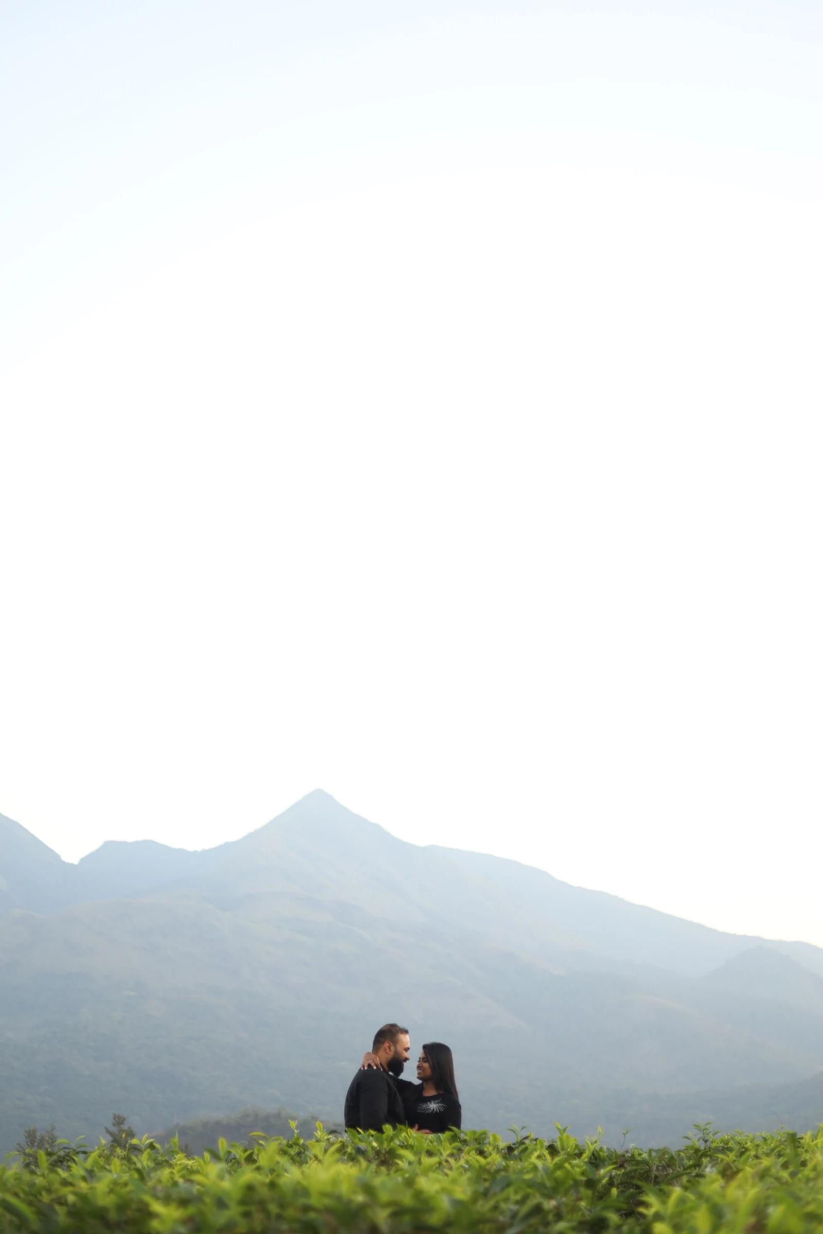 A distant couple beneath a broad sky and mountain ridge