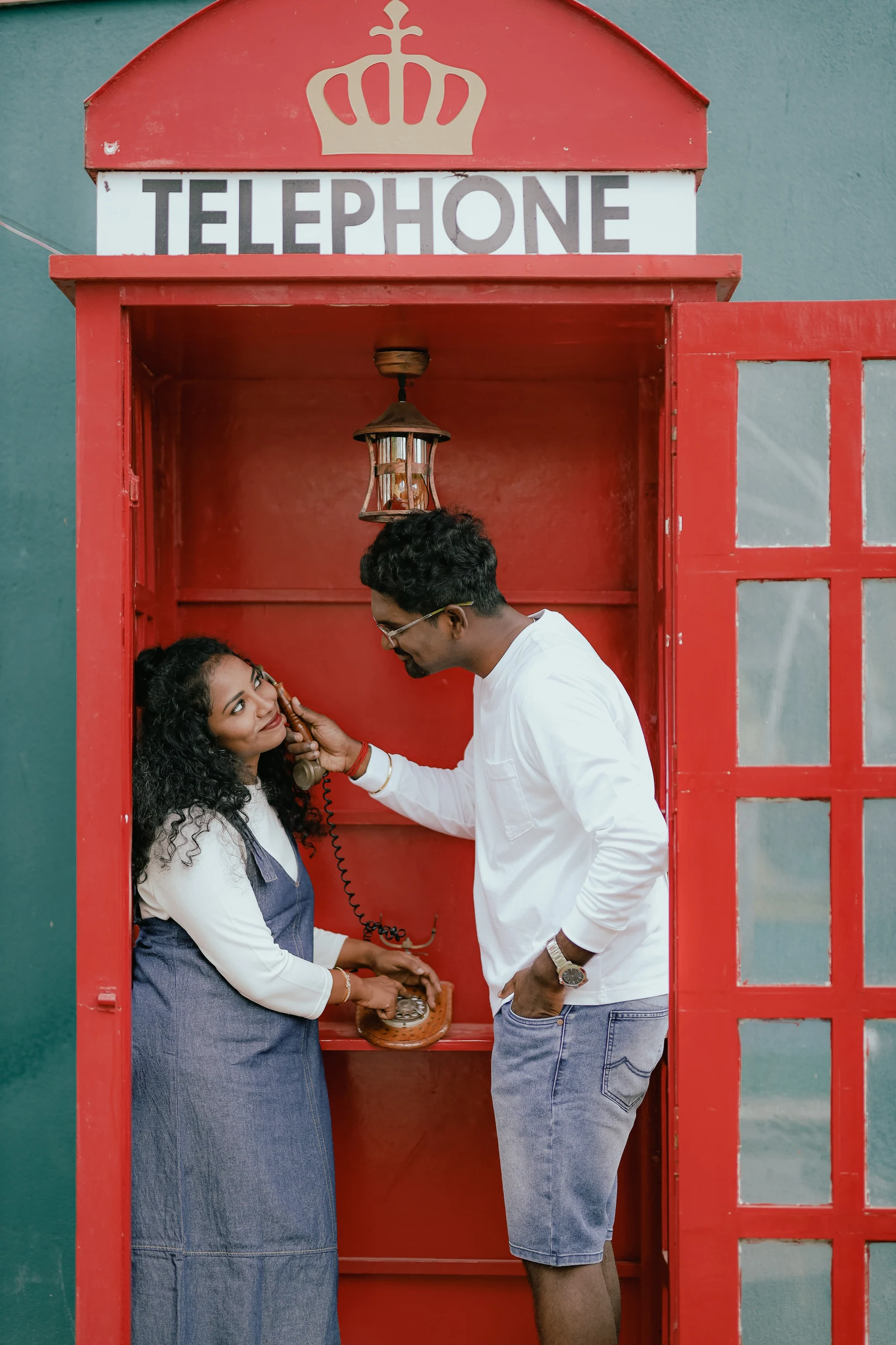 Couple laughing beside a red telephone booth
