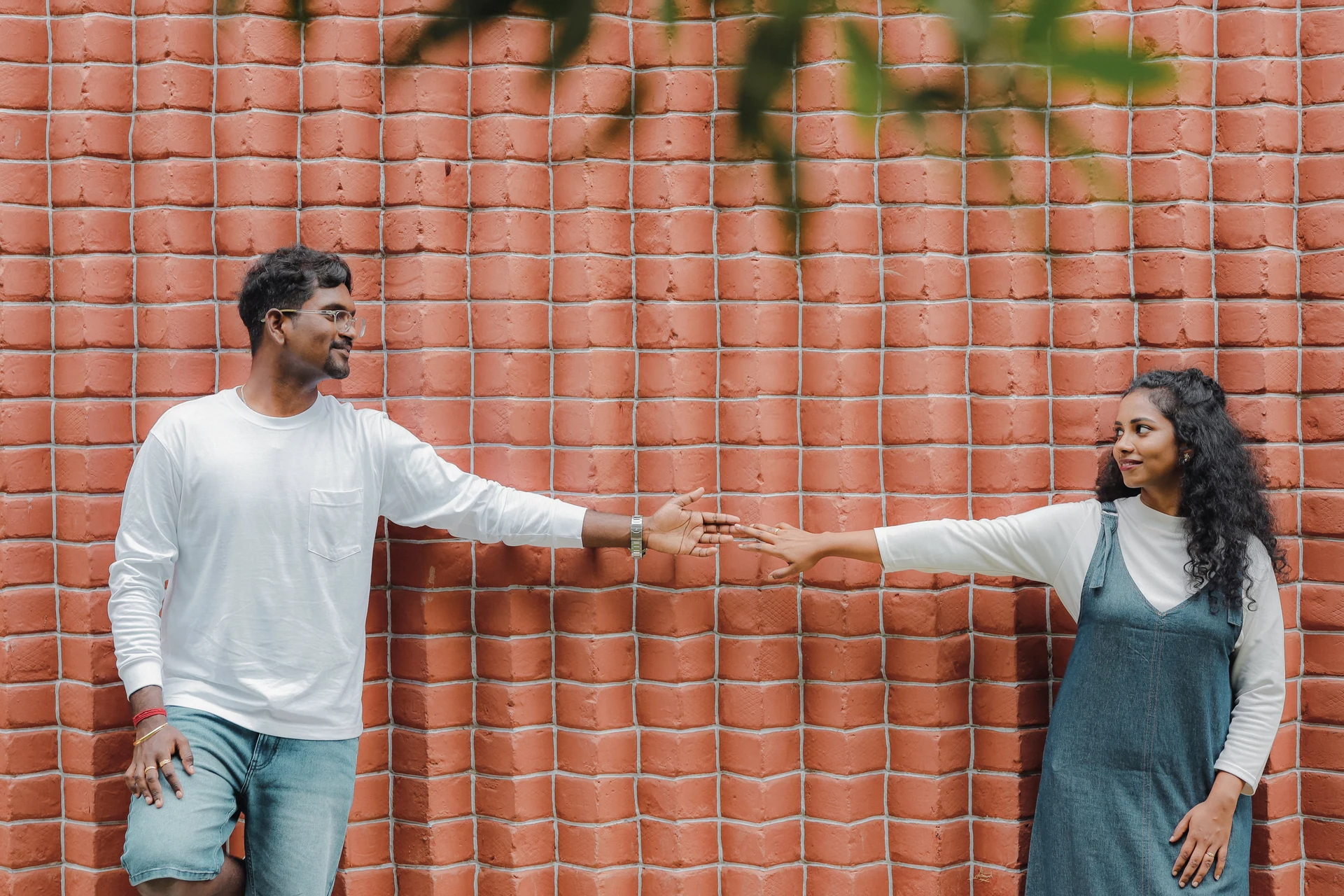 Couple reaching for each other against a red tiled wall