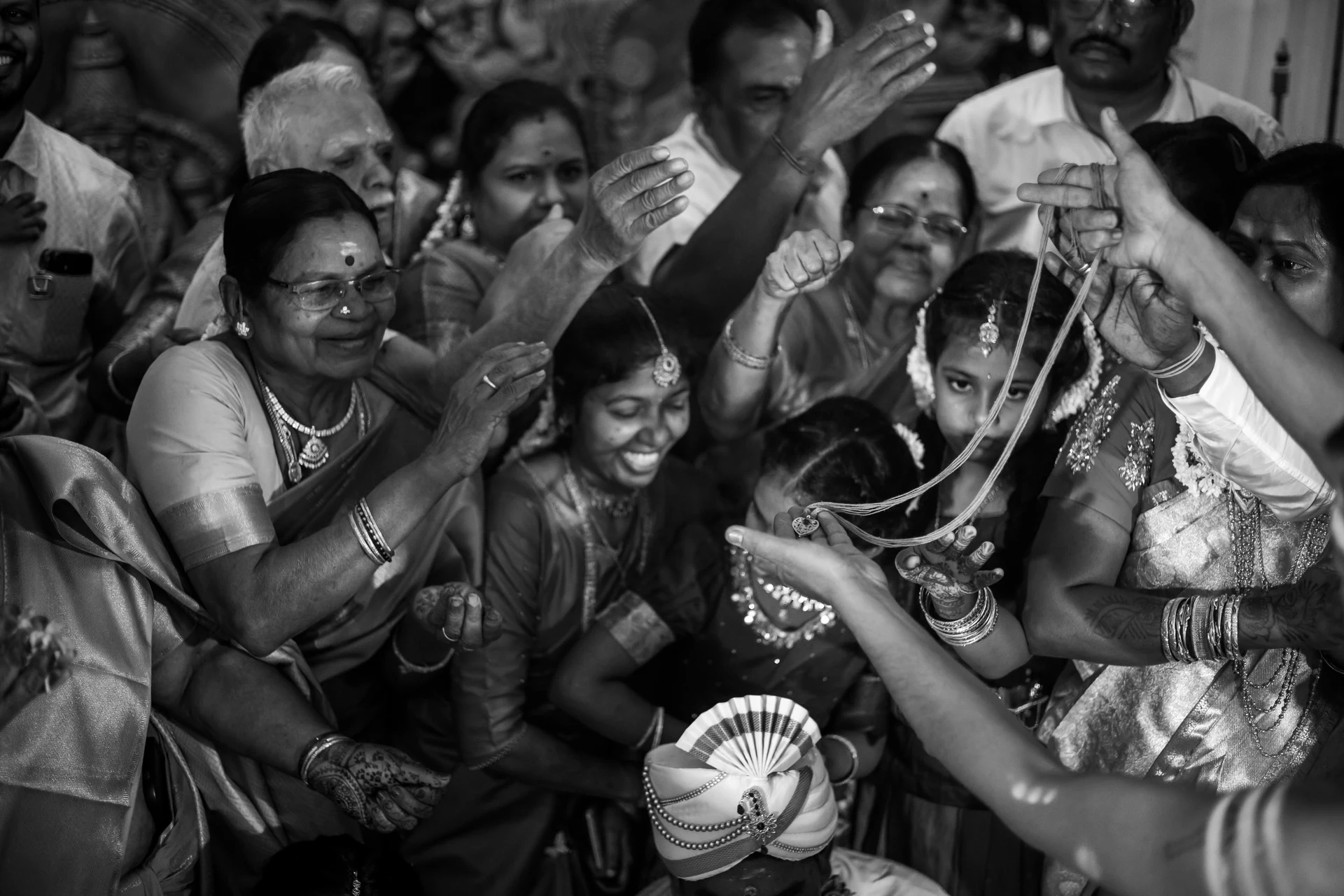 Smiling faces gathered closely around a couple during a ceremony