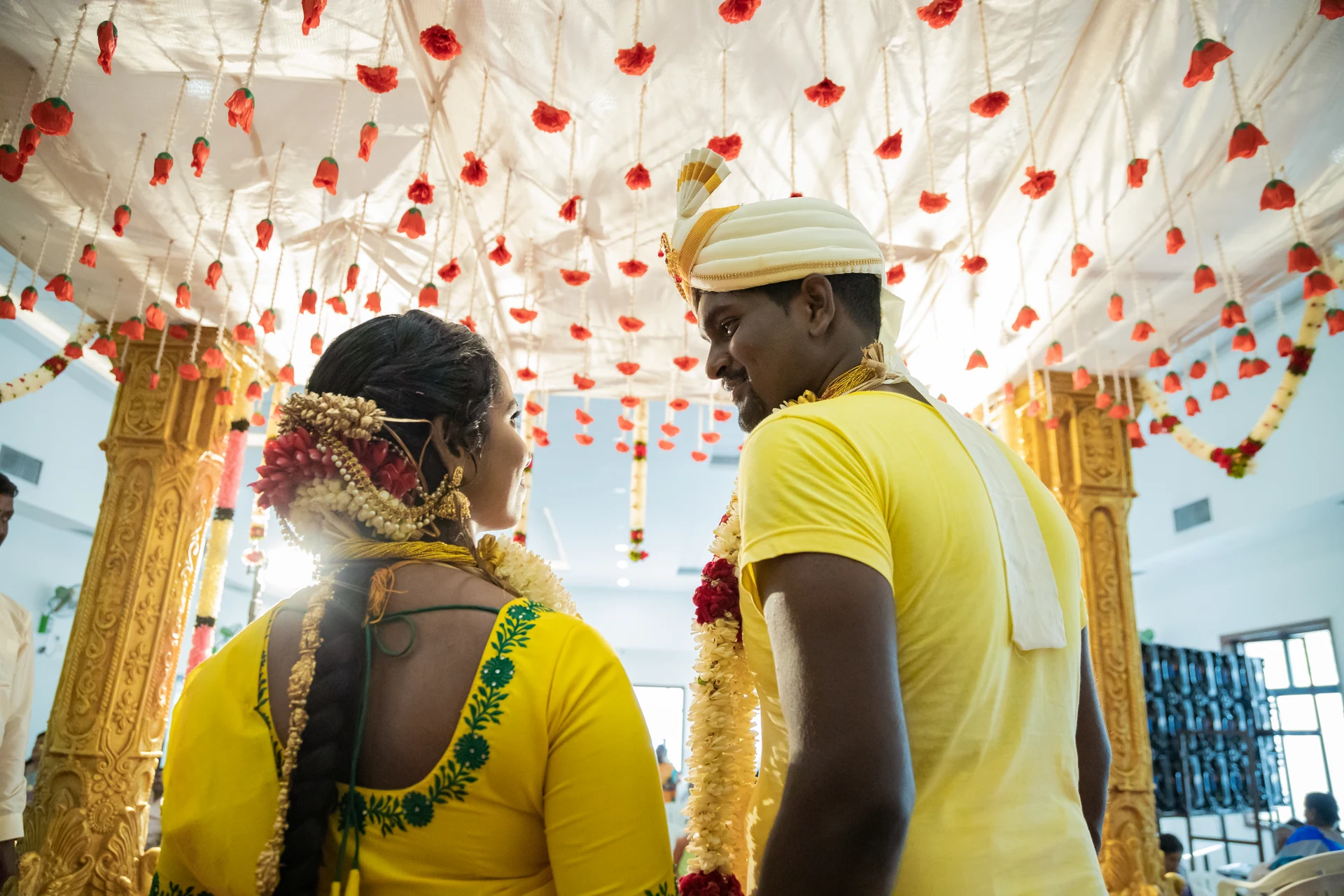 Couple looking back beneath strings of red and white flowers