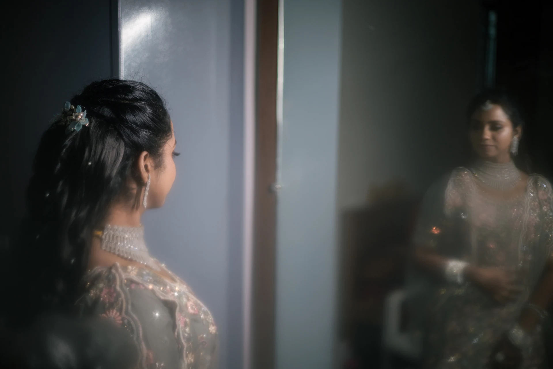 A woman looking towards her reflection in a softly lit mirror