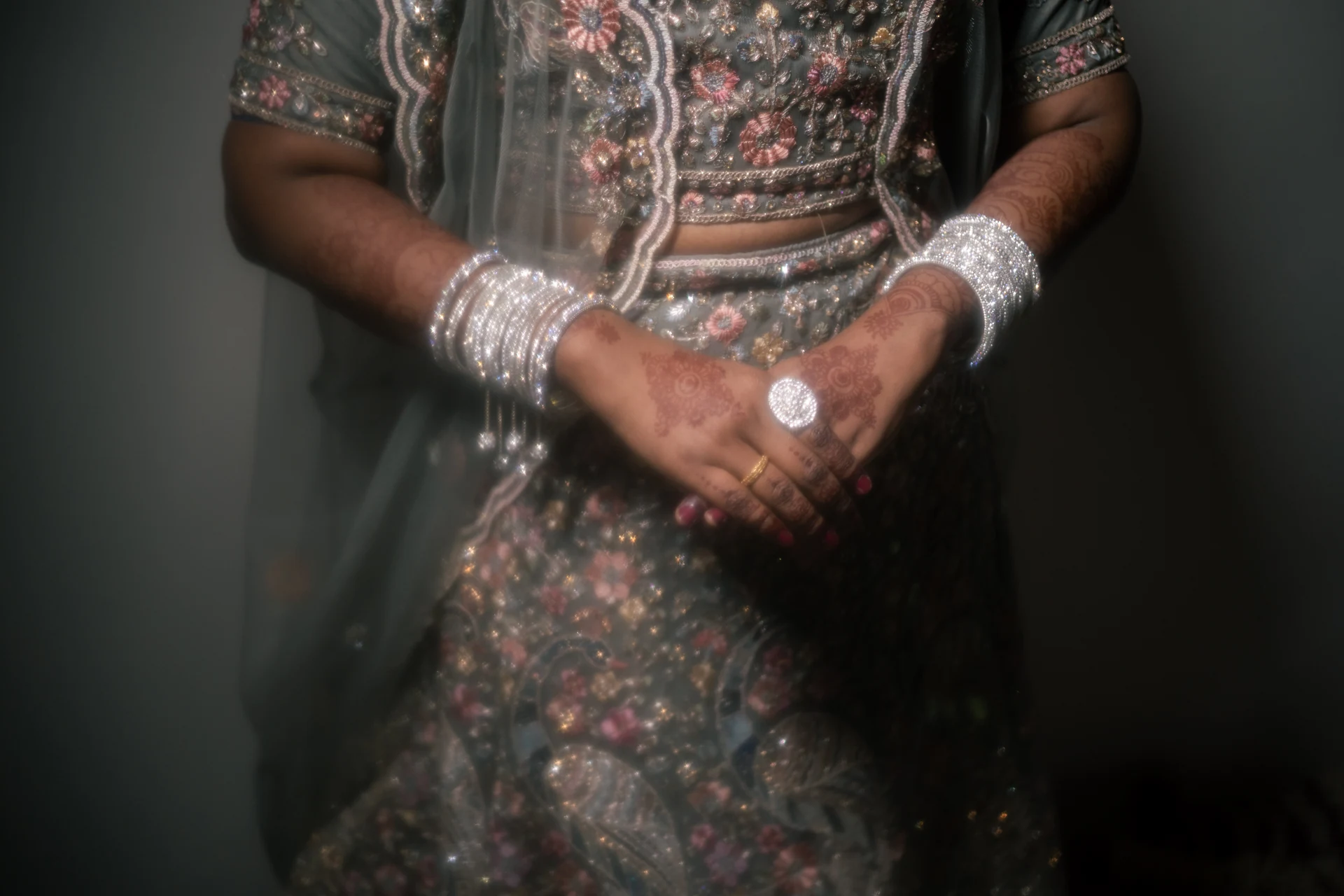 Close view of clasped hands and embroidered clothing