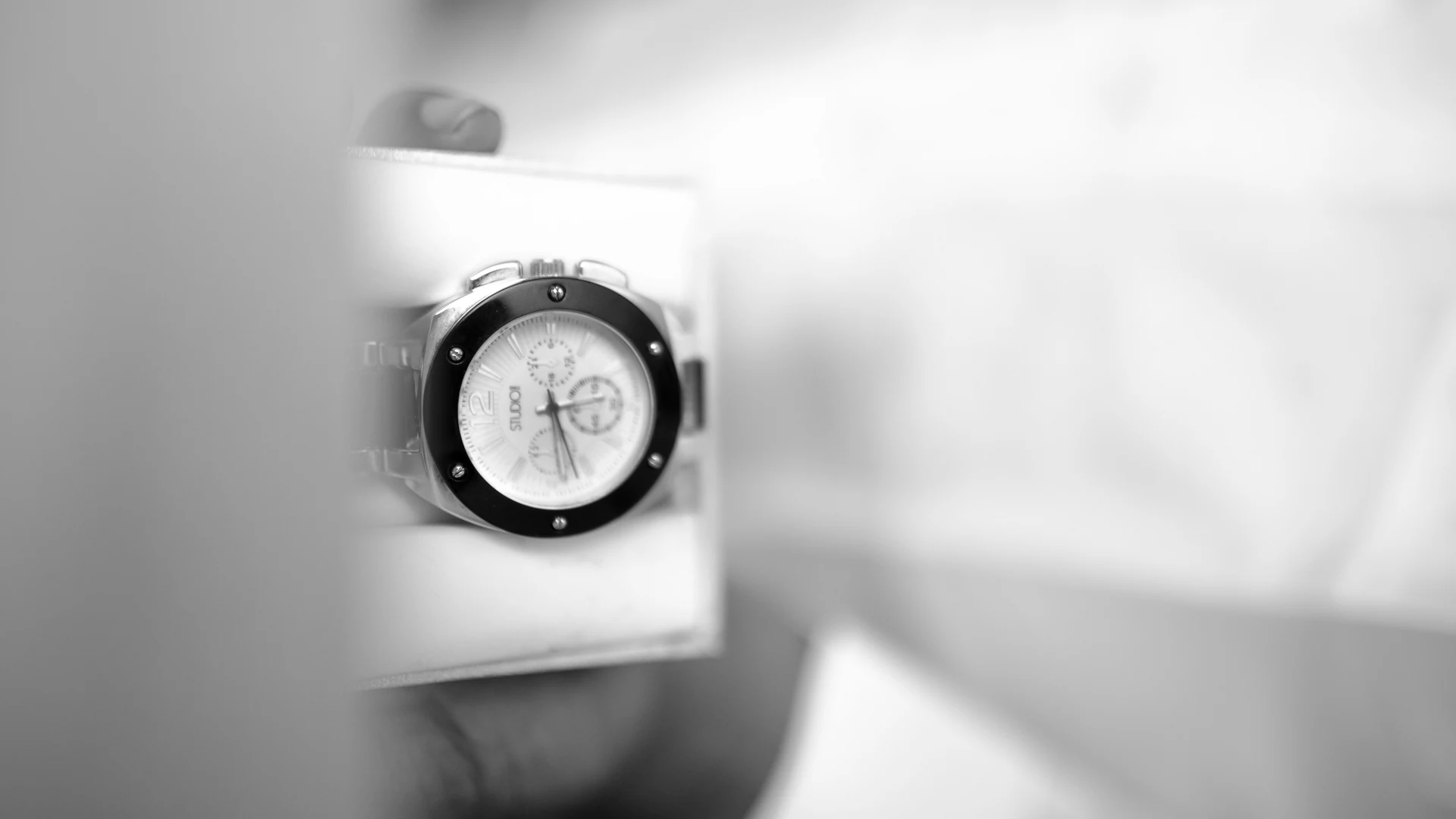Black-and-white close view of a wristwatch being worn
