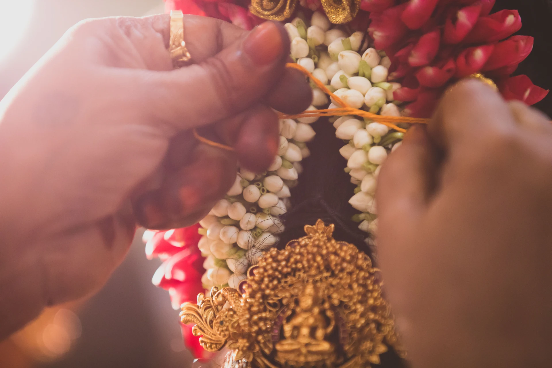 Close view of hands and flowers in warm ceremony light