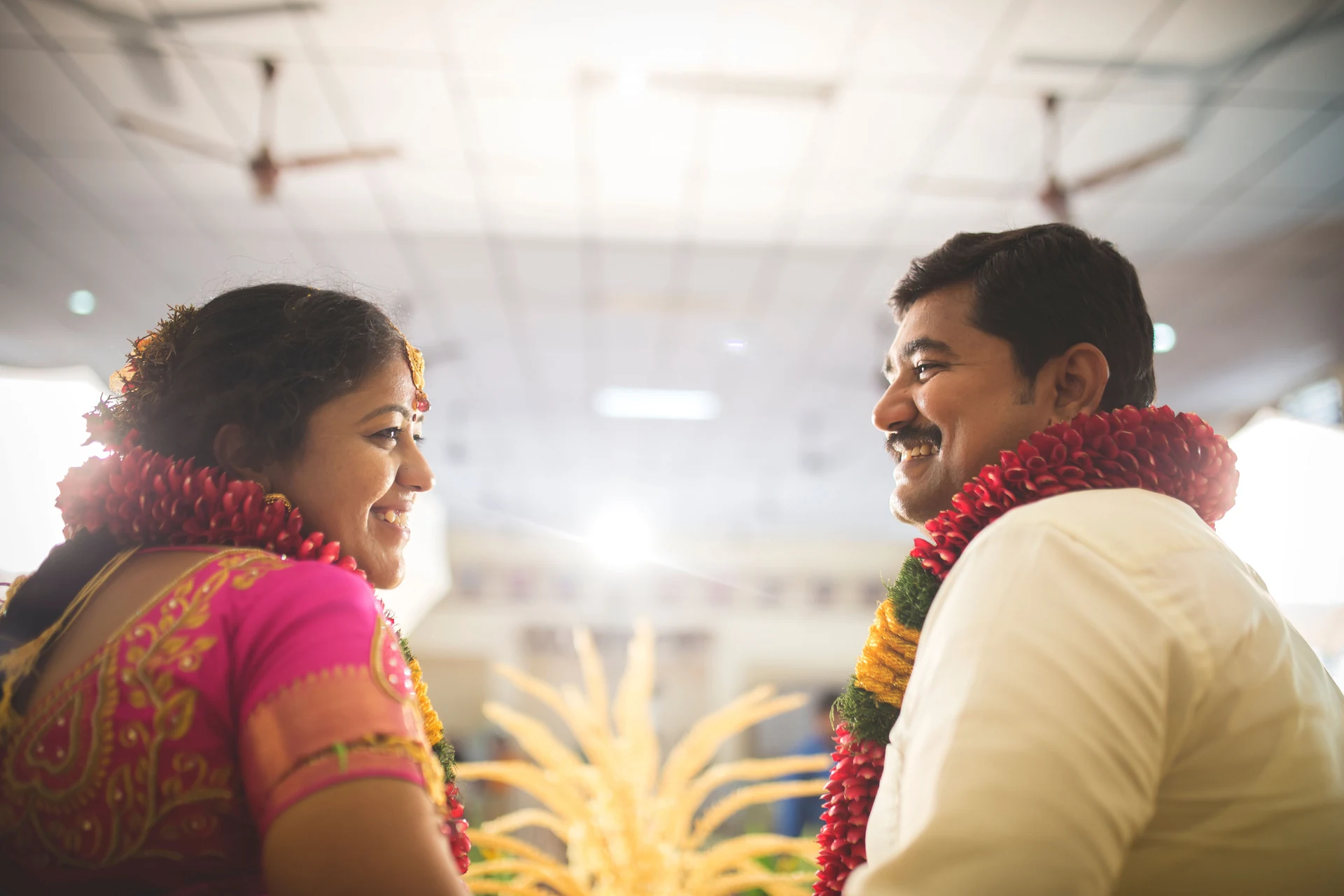 Couple turning towards each other with flowers around their shoulders