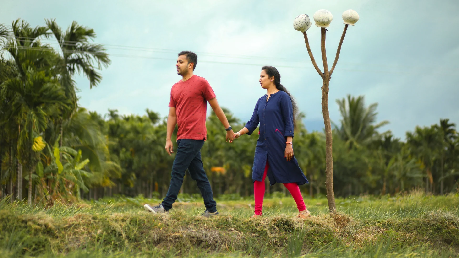 Couple holding hands while walking across an open green space