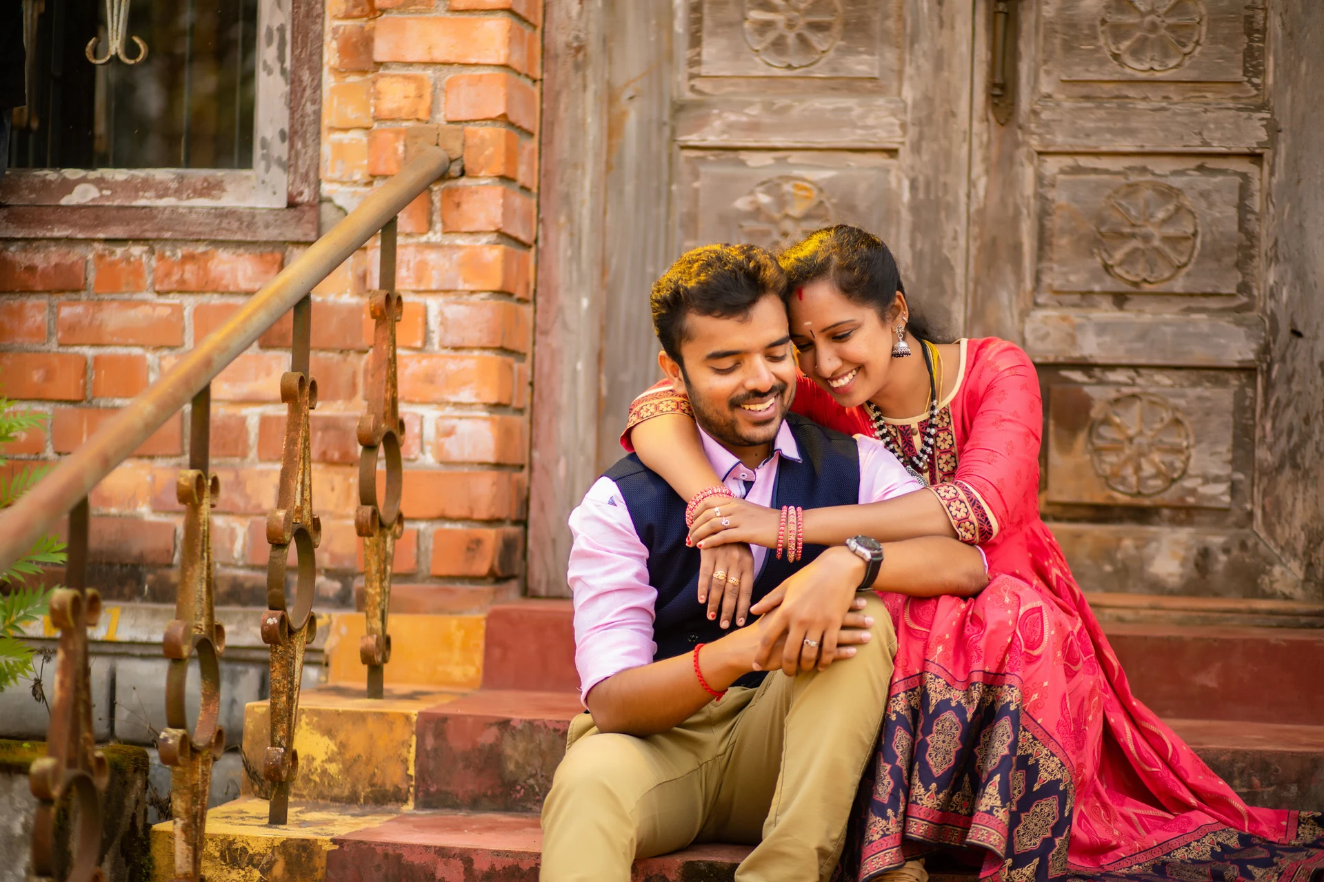 Couple sitting close on steps outside a weathered wooden doorway