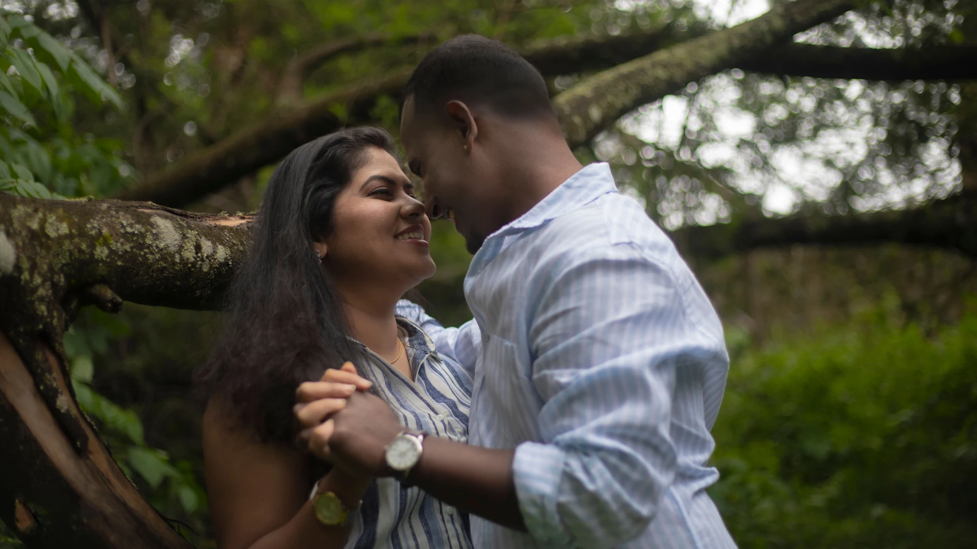 Couple leaning close together beneath a broad tree branch