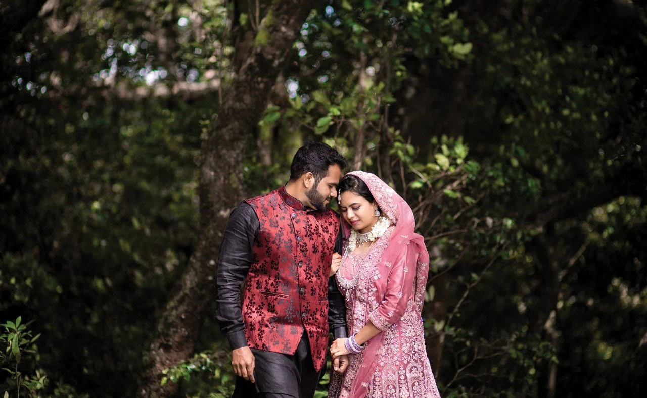 Couple leaning towards each other beneath leafy trees