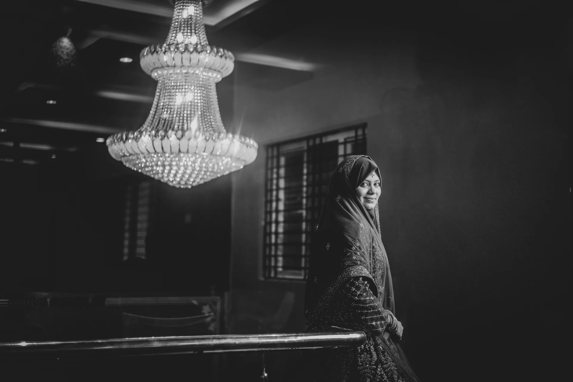 Black-and-white portrait of a woman beneath a chandelier