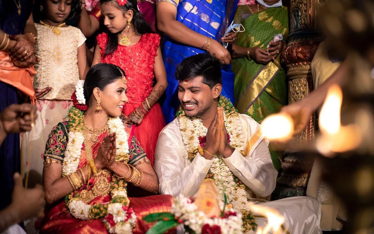 Couple seated together during a ceremony with people gathered behind them