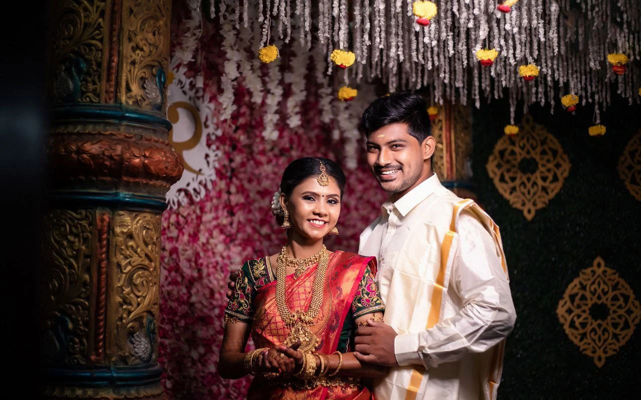 Couple standing together beneath strings of flowers